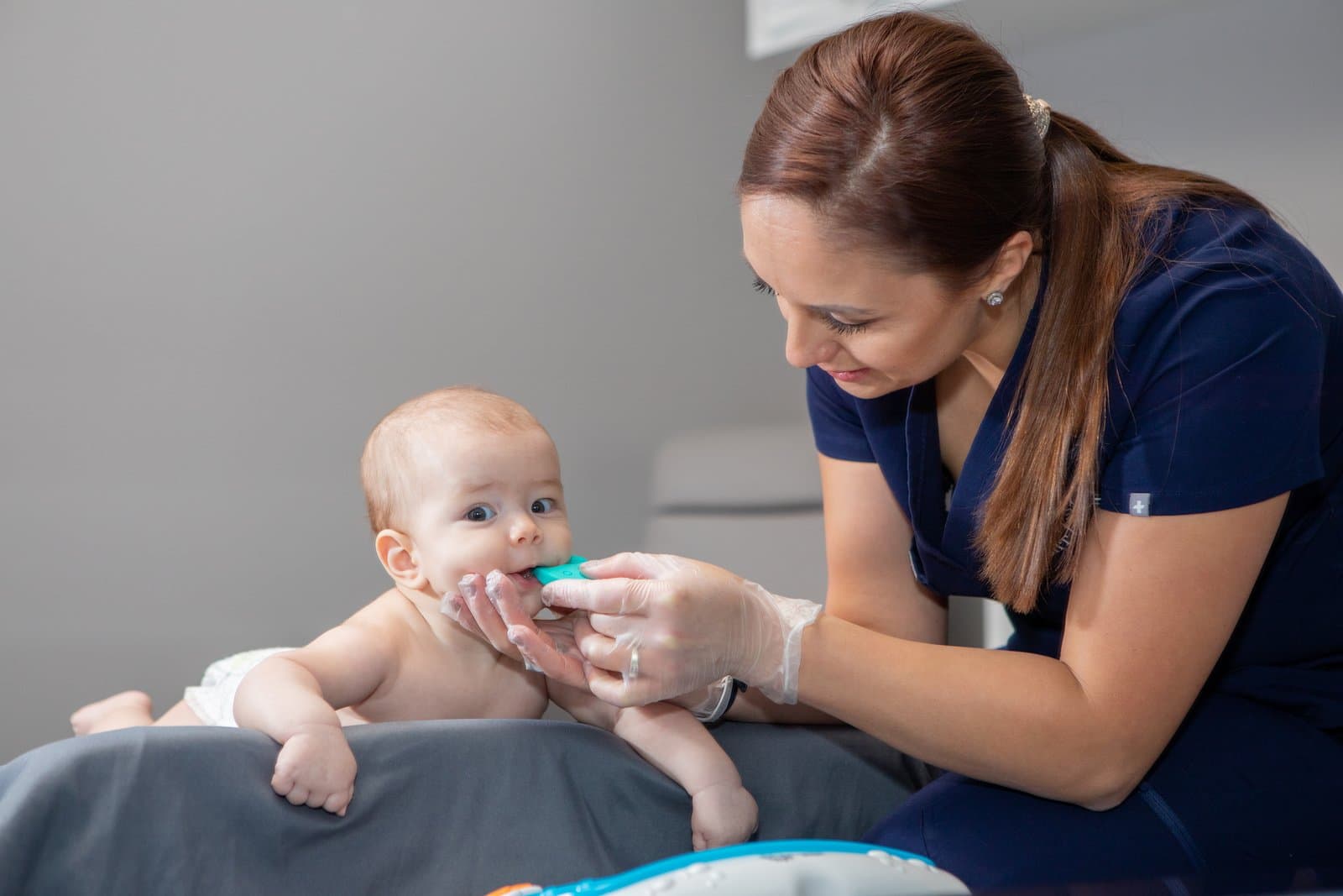 Margaret in navy scrubs working with an infant during a feeding and oral function session